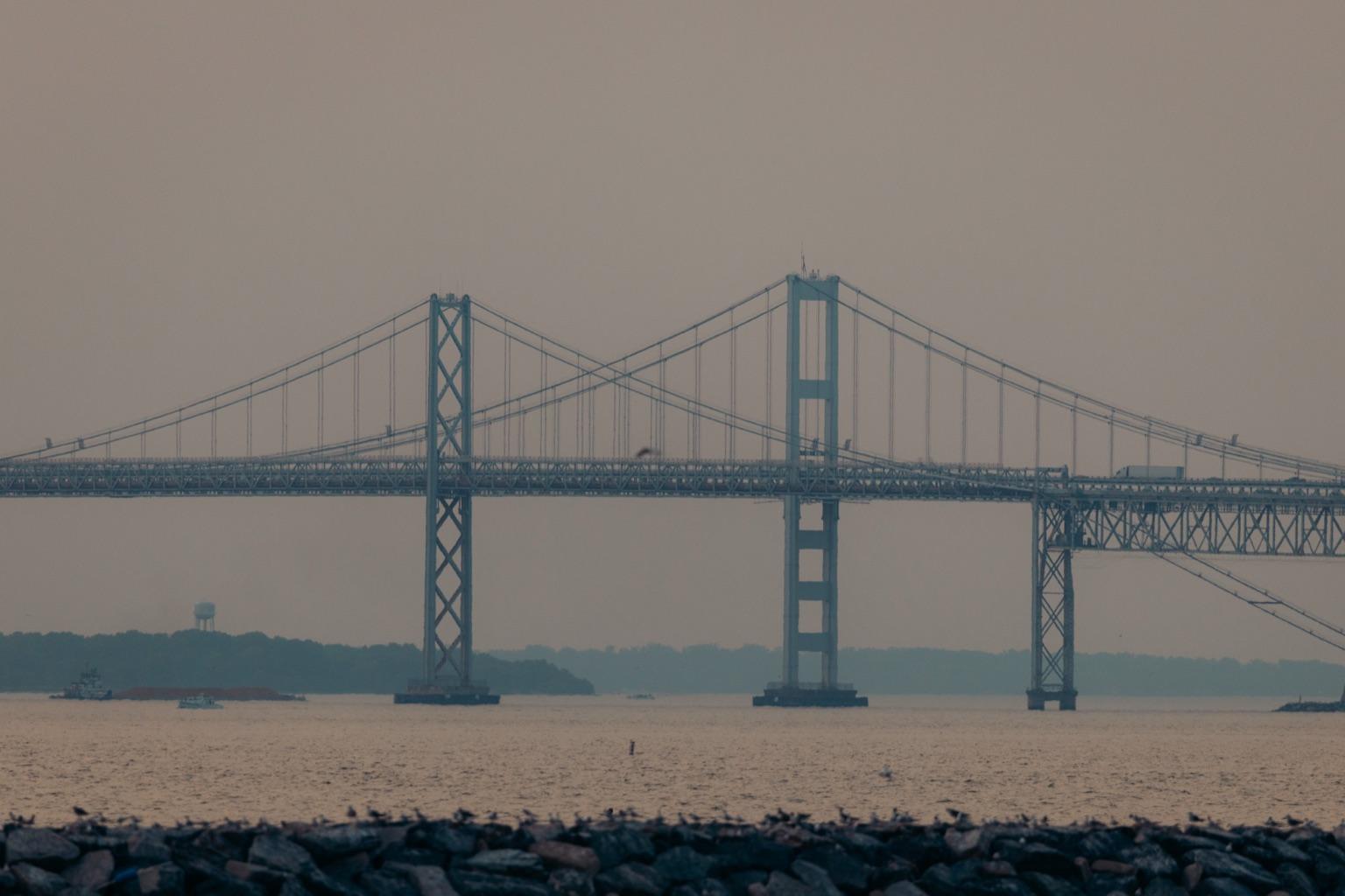 Suspension spans of the Chesapeake Bay Bridge on a hazy day, seen from the rocks at Sandy Point